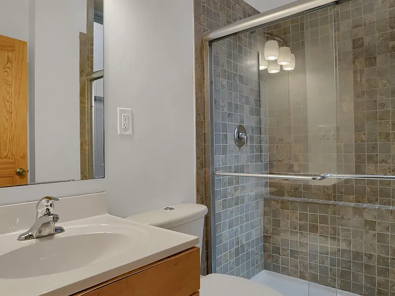 Bathroom Main Level - vanity, tiled shower, marbled tile floor, glass by-pass shower doors