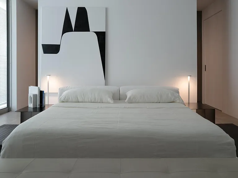 Minimalist Bedroom with Statement Design _ A serene escape featuring soft ambient lighting, plush textures, and a striking contrast of monochrome elements. Floor-to-ceiling windows enhances the luxurious feel of the space.