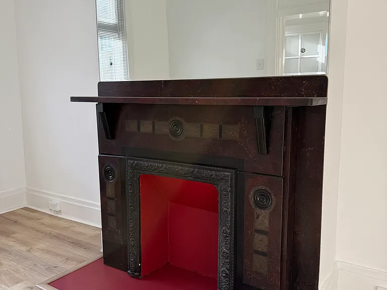 1st Floor Front Room_ Living Room, with a lot of natural light flowing in, another antique fireplace w/ a bright red hearth (& mirror above it) and brand new Luxury Vinyl Plank flooring (wood-like and warm)