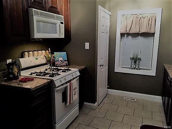 Updated kitchen with custom wood cabinetry, granite countertops, ceramic flooring and new window overlooking the fenced backyard..