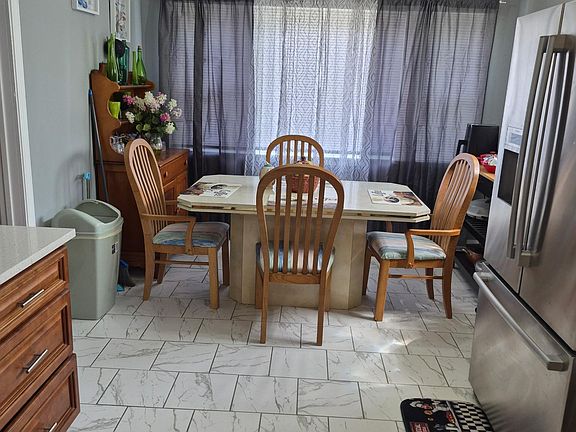 Eat-in kitchen with a dining nook, large window with curtains, and durable tile flooring for easy upkeep.