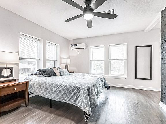Large room with minisplit AC, queen bed, hybrid mattress, night stand, full length mirror, and desk with chair and smart TV.