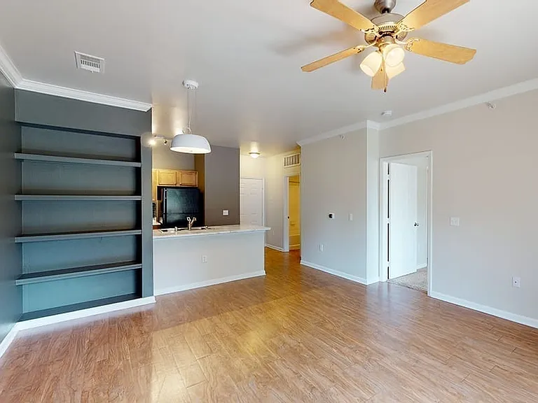 Apartment kitchen, dining and living room with wood-style flooring.