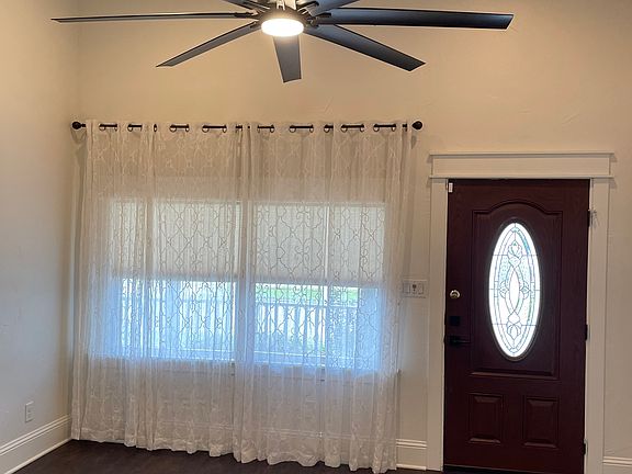 Living room has soaring tall ceiling and ceiling fan.