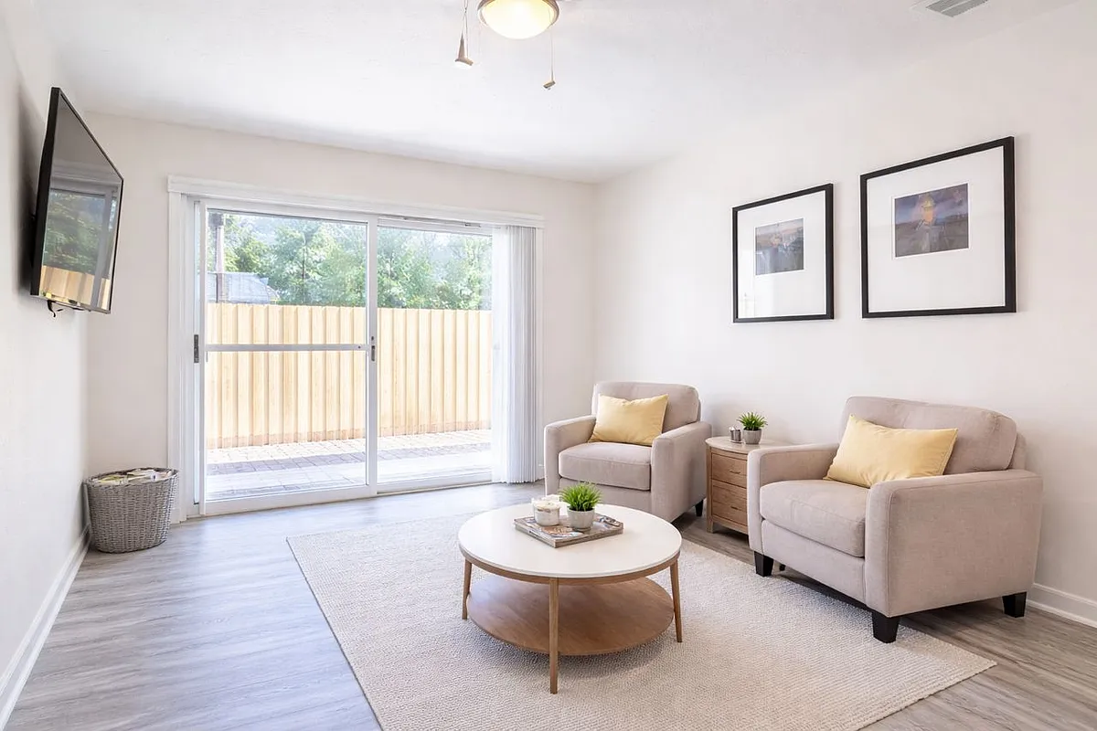 Comfortable shared living space with wall-mounted TV, ceiling fan, and sliding door to the fenced backyard - 2006 E Hanna Ave #3