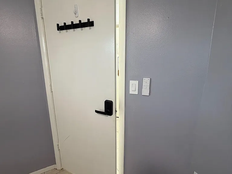 Entry area with tile flooring, painted walls, and a door featuring a keyed handle and wall-mounted coat hooks.