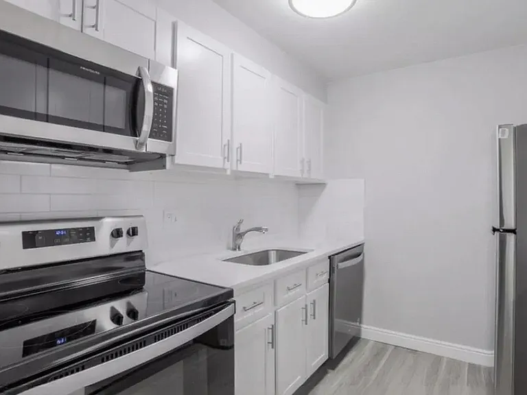 Modern kitchen with sleek stainless steel appliances, pristine white cabinetry, and elegant quartz countertops.