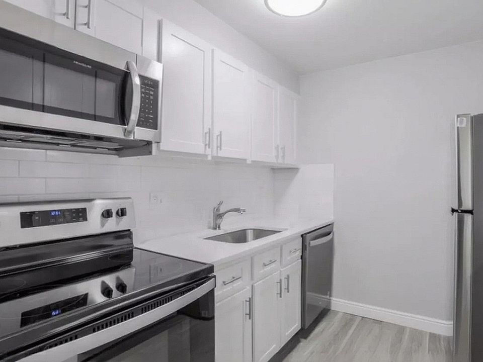 Modern kitchen with sleek stainless steel appliances, pristine white cabinetry, and elegant quartz countertops.