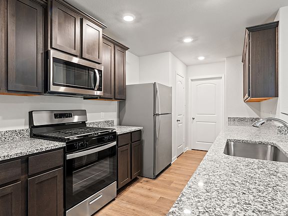 The kitchen of the Cedar has beautiful wood cabinetry and sprawling granite countertops.