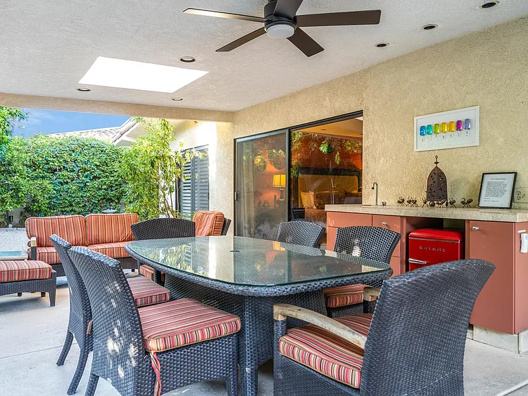 Outdoor dining area under shade structure with ceiling fan.