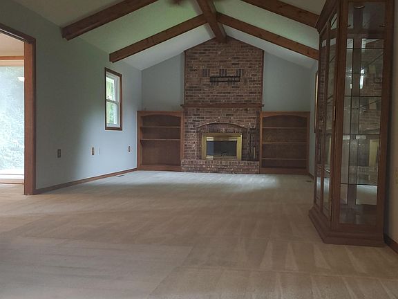 Large living room with built-in shelves, a wood-burning fireplace and a curio cabinet.