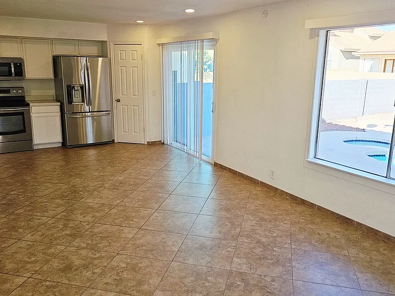 Open kitchen and dining area featuring stainless steel appliances, abundant natural light, and sliding door access to the backyar perfect for indoor-outdoor living.