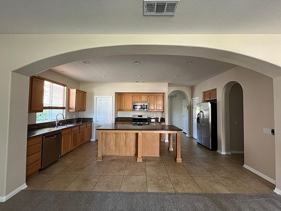 Oversize island with granite countertops, large porcelain tile flooring & stainless steel appliances.