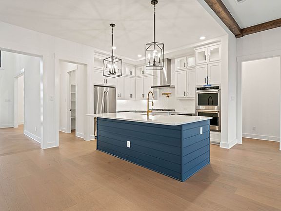 The kitchen has a beautiful blue island with quartz countertops.