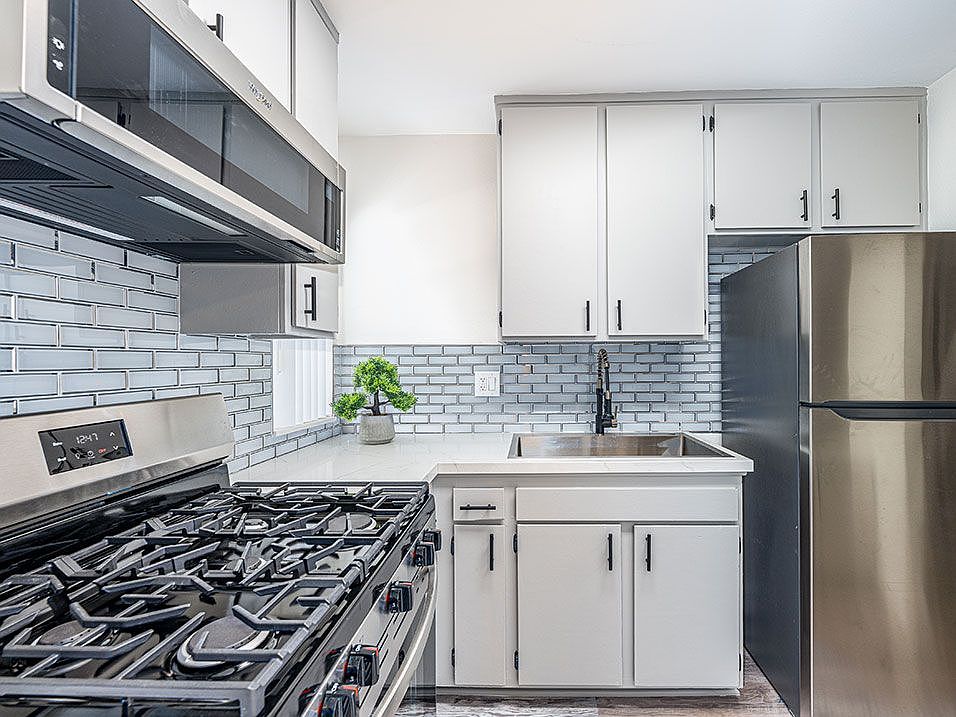 Tiled kitchen with stainless steel fridge, oven, and miocrowave.