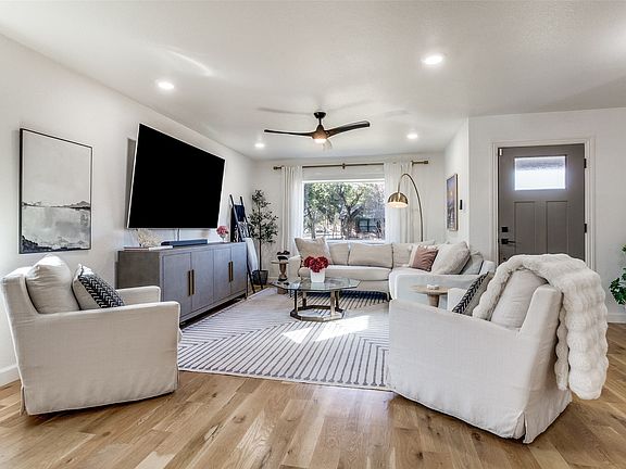 Spacious living area featuring light wood-finish flooring, recessed lighting, a ceiling fan, and a front entry door with an upper glass panel