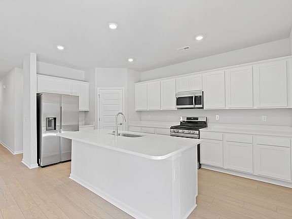 Bright kitchen with loads of cabinet storage, refrigerator, pantry, solid surface counter tops and recessed lighting!