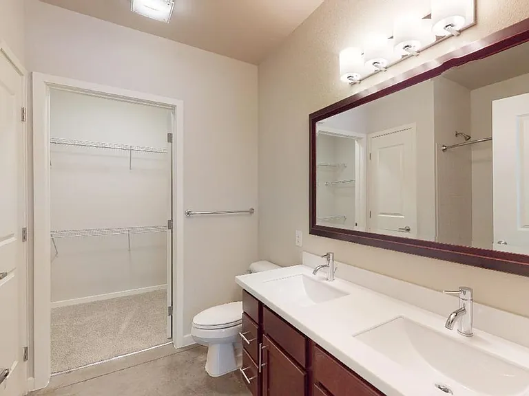 Apartment bathroom with polished concrete flooring and double sinks.