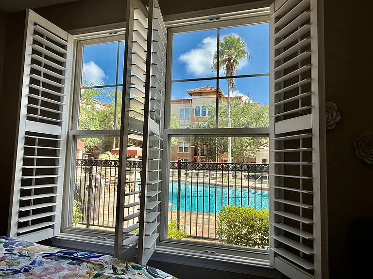 Primary bedroom plenty of natural light Bahamas shutters for style and privacy