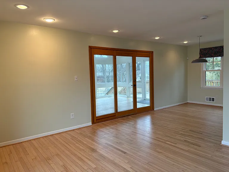 Living room and dining room with doors to large glass sun room and back deck.