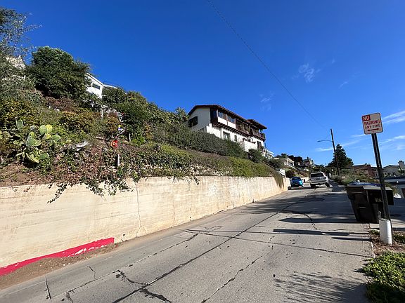 This Spanish-style home is on a large piece of property, so it feels very private. There's space to park 1 slim vehicle where you see the blue-green car in this photo.
