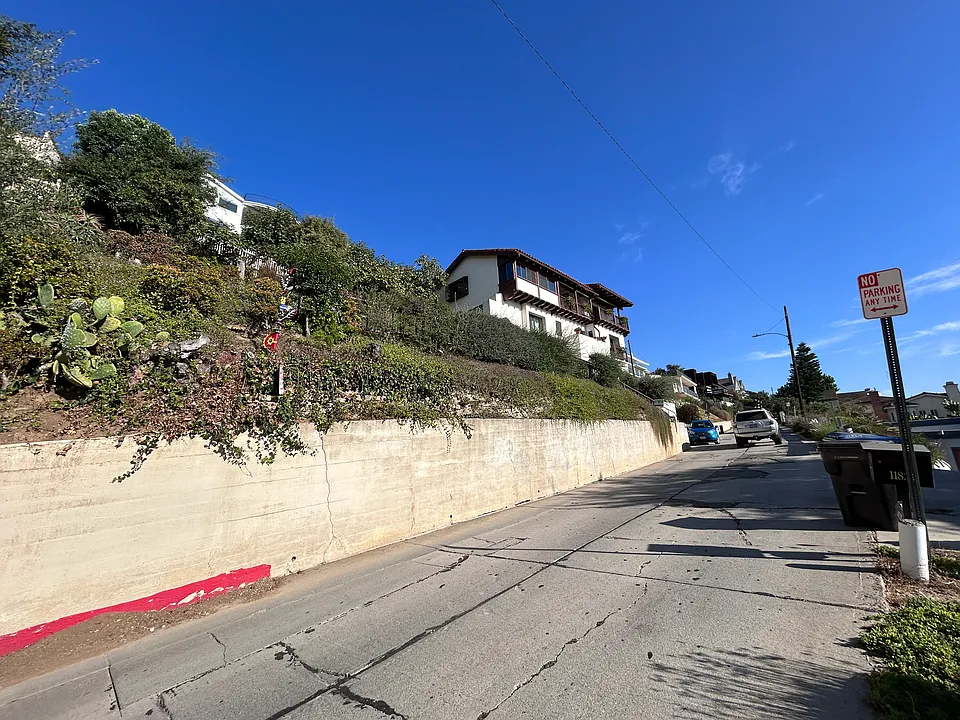 This Spanish-style home is on a large piece of property, so it feels very private. There's space to park 1 slim vehicle where you see the blue-green car in this photo.
