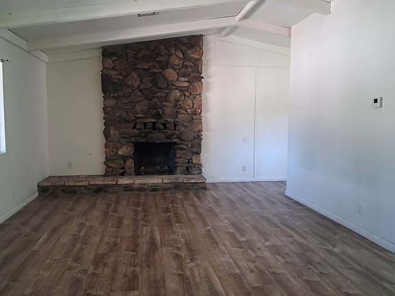 Rock woodburning fireplace in living room, with vaulted ceiling.
