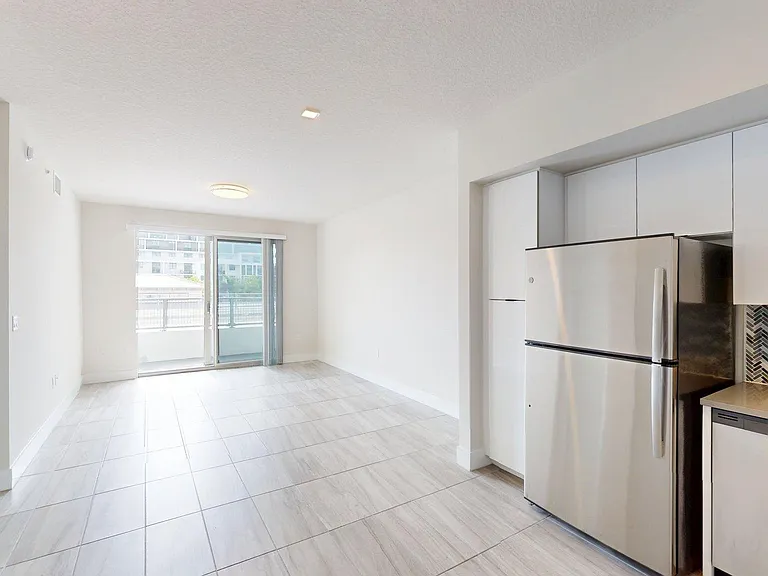Apartment kitchen with stainless steel appliances, dining space, and living space.