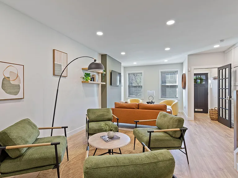 Open-concept living area with recessed lighting, wood-look floors, ample seating, and easy flow to the entry and stairs.