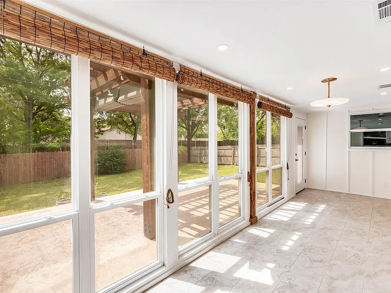 Sunroom featuring extensive window panels, woven wood blinds, recessed lighting, and tile flooring