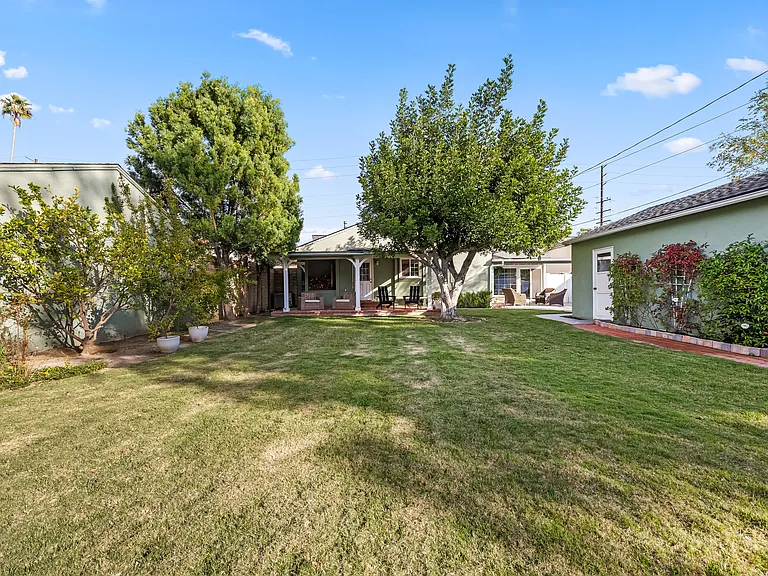 Spacious, fully fenced backyard with two distinct patio sections and seating in each.