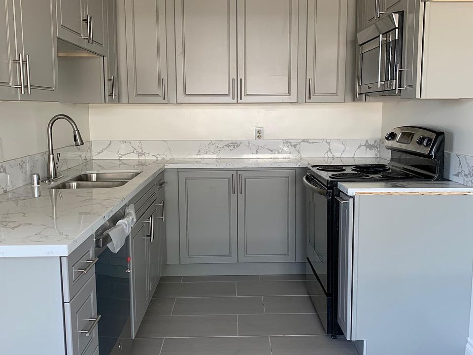 Kitchen with stainless dishwasher, range, microwave (white refrigerator comes in this apartment) - gray cabinets and lots of counter space, pull out condiment/spice cabinet