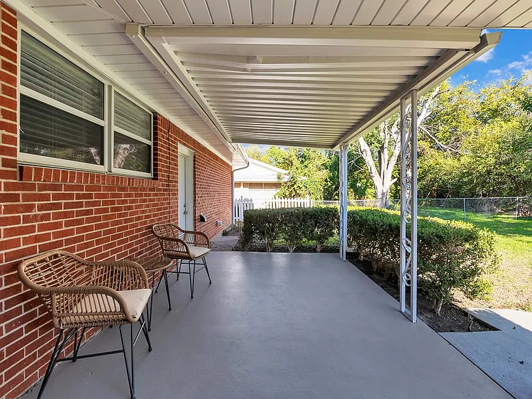 Covered patio with outdoor seating and private fenced yard.