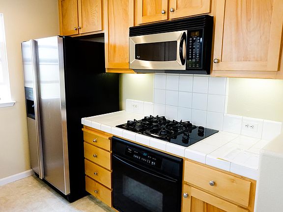 Kitchen with stainless steel fridge, gas stove, oven, and built-in microwave
