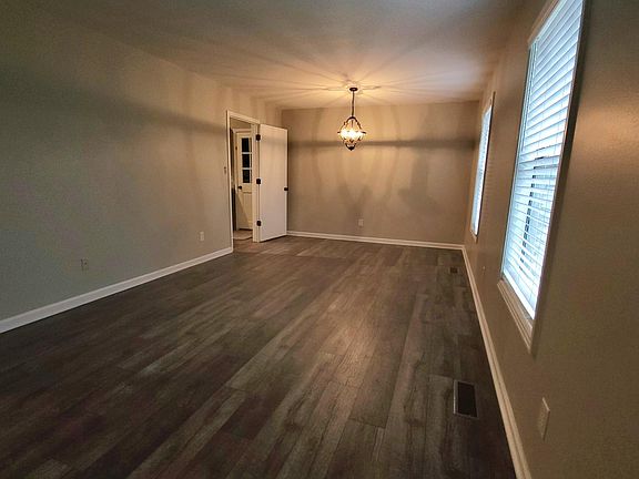 The large dining / living room combination has large windows with blinds overlooking the front yard.