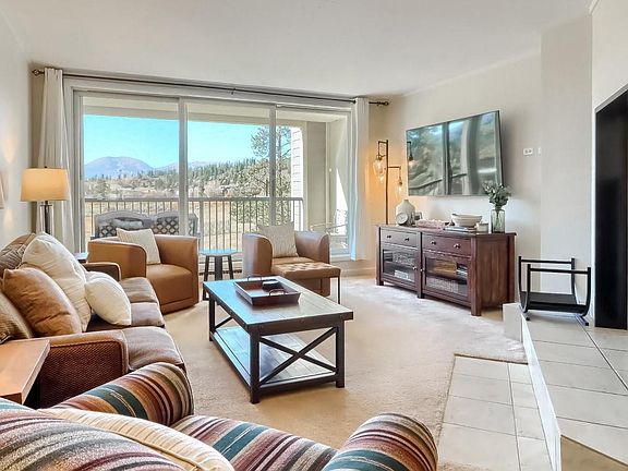 Living room with pullout couch, new 65" smart TV, and wood-burning fireplace.