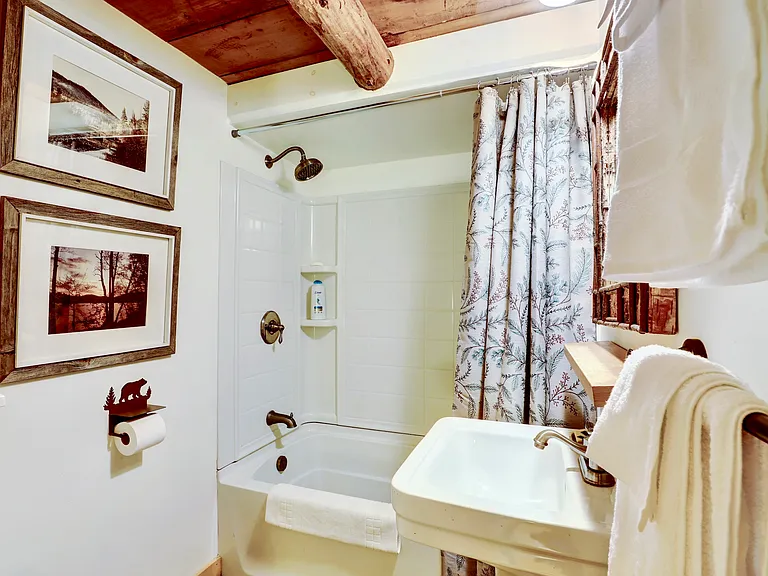 Full Bathroom with tub shower, sink and toilet. A small electric space heater is built into the wall.
