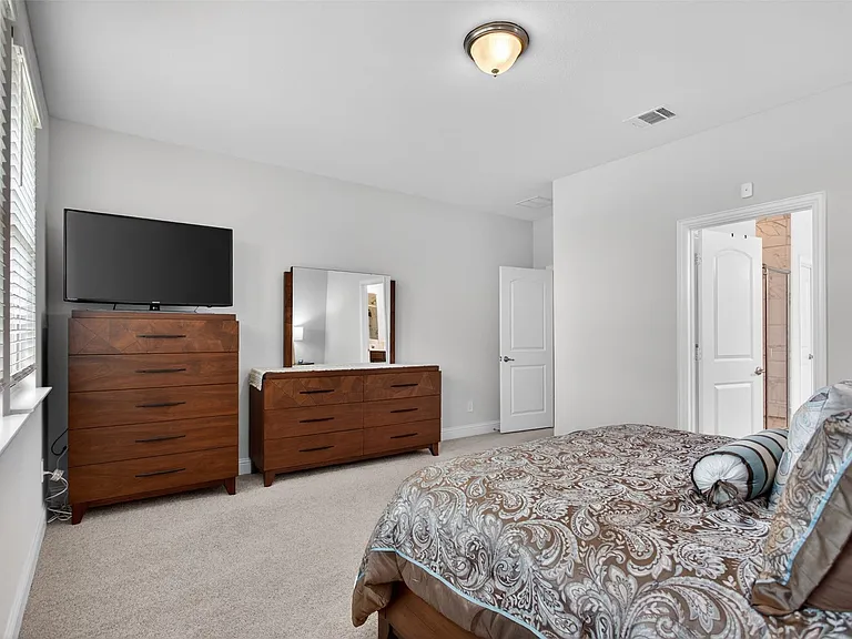Carpeted bedroom featuring neutral wall tones, a ceiling-mounted light fixture, and an arched interior doorway