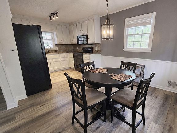 Eat-in kitchen with ample white cabinetry, granite-look counters, and black appliances, plus a dinette by the window.