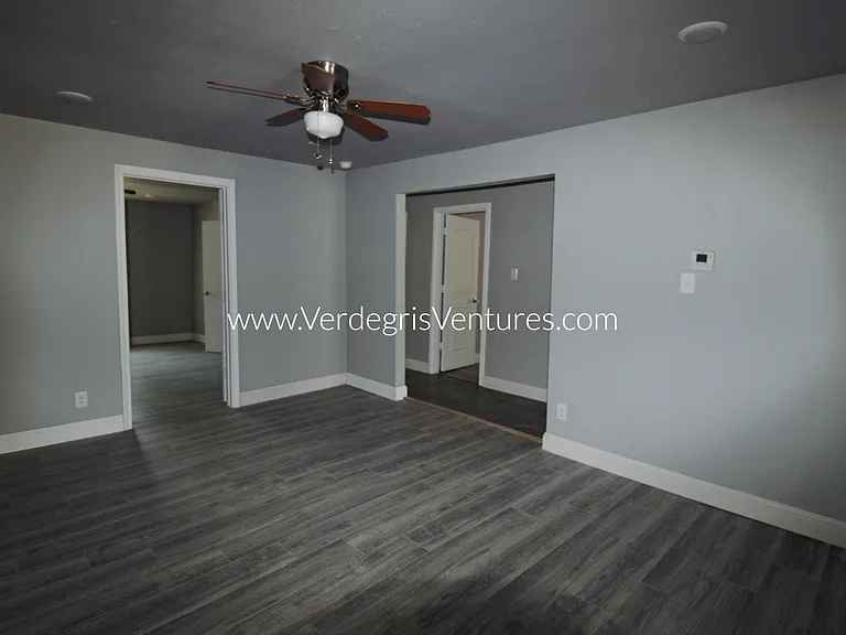 A spacious dining room sits at the very center of the home, serving as a natural hub between the kitchen and bedrooms. It features a ceiling fan and also functions as a convenient hallway connecting the main living areas