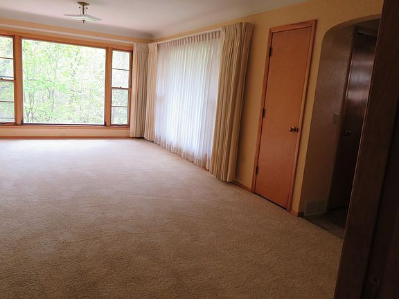 Living room with large picture windows looking out to woods.