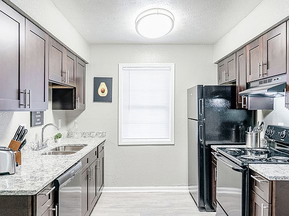 Gorgeous kitchen with granite countertops, cookware, toaster, utensils, and black appliances.