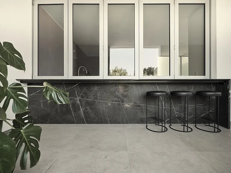 Sophisticated Outdoor Bar with Architectural Stonework _ Featuring a striking black marble base and seamless pass-through windows, this outdoor bar is designed for both style and functionality.