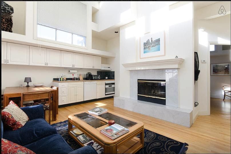 View of living room with gas fireplace; kitchen to left.