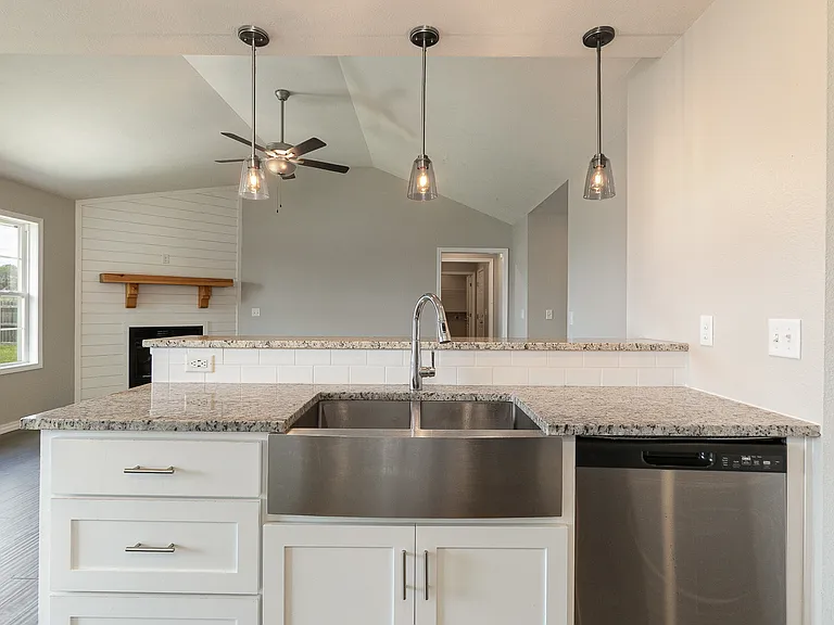 Kitchen with granite countertops, stainless steel appliances and pendant lights over bar counter