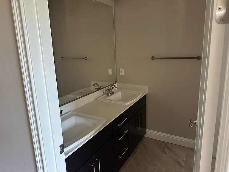 Spacious 3rd-floor bathroom with dual sinks, modern vanity and shower/tub, serving two bedrooms.