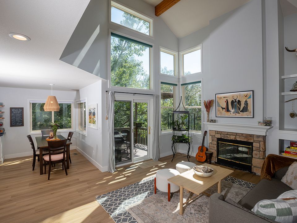 Bright, double-story family room with a gas fireplace. Sliding doors lead to an outdoor deck with Weber gas grill, table for three and beautiful mountain views.