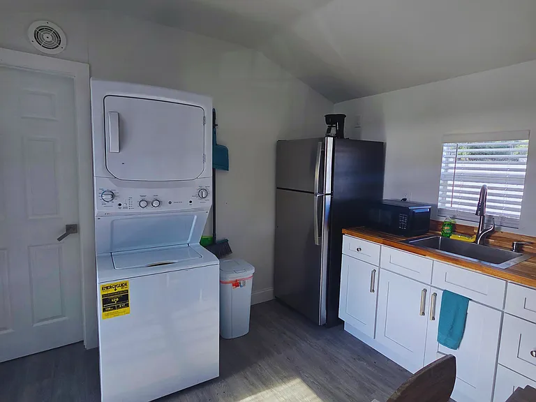 Laundry space with washer, cleaning tools, and trash bin