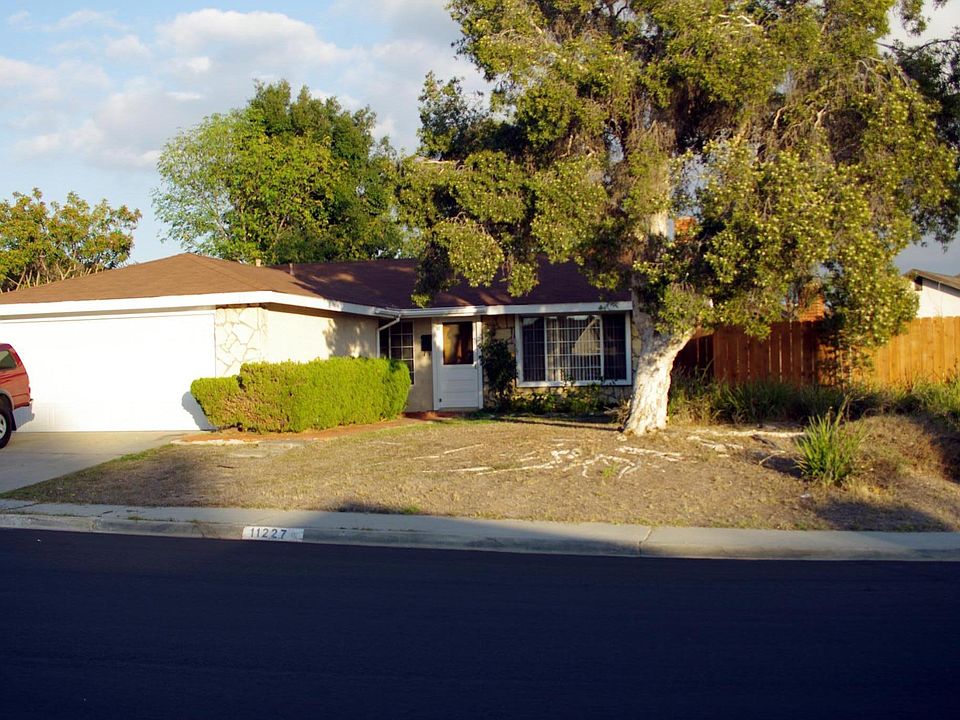 Front of house looking East. Shows fenced area on South side of house where pool is located.