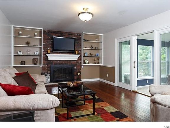 Large family room with refinished hardwood floors, wood burning fireplace and newer Pella Doors to t